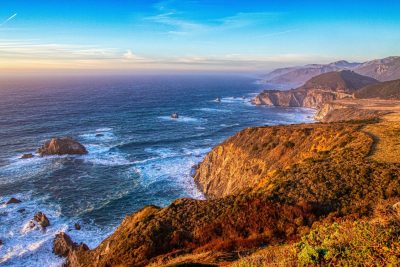 Big Sur coastline with cliffs and Pacific Ocean waves at sunset in California.